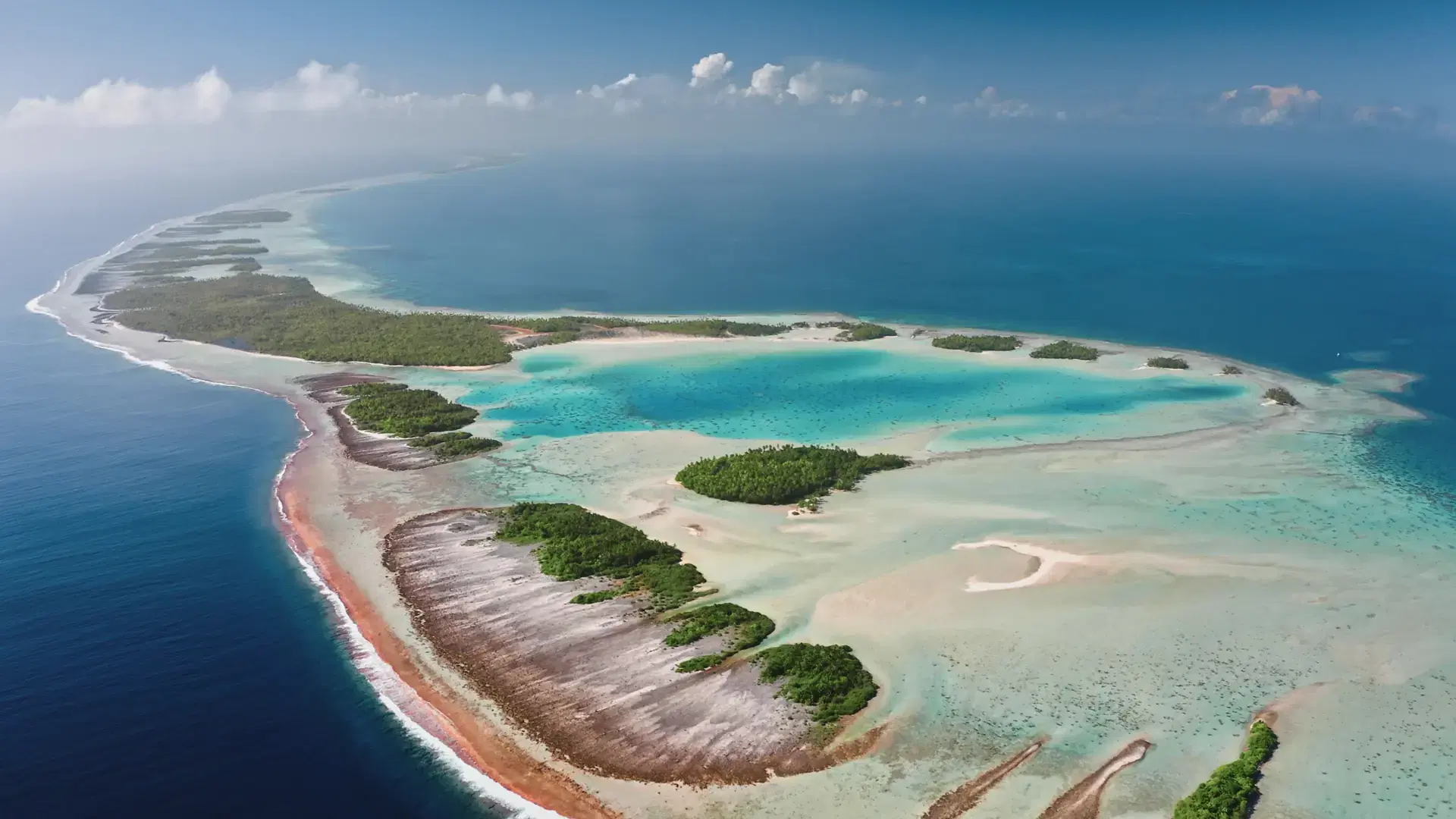 French Polynesia, Rangiroa island: Aerial view of largest atoll in the Tuamotu archipelago, featuring a turquoise lagoon and coral reef. Wild nature travel landscape. Drone flight panorama