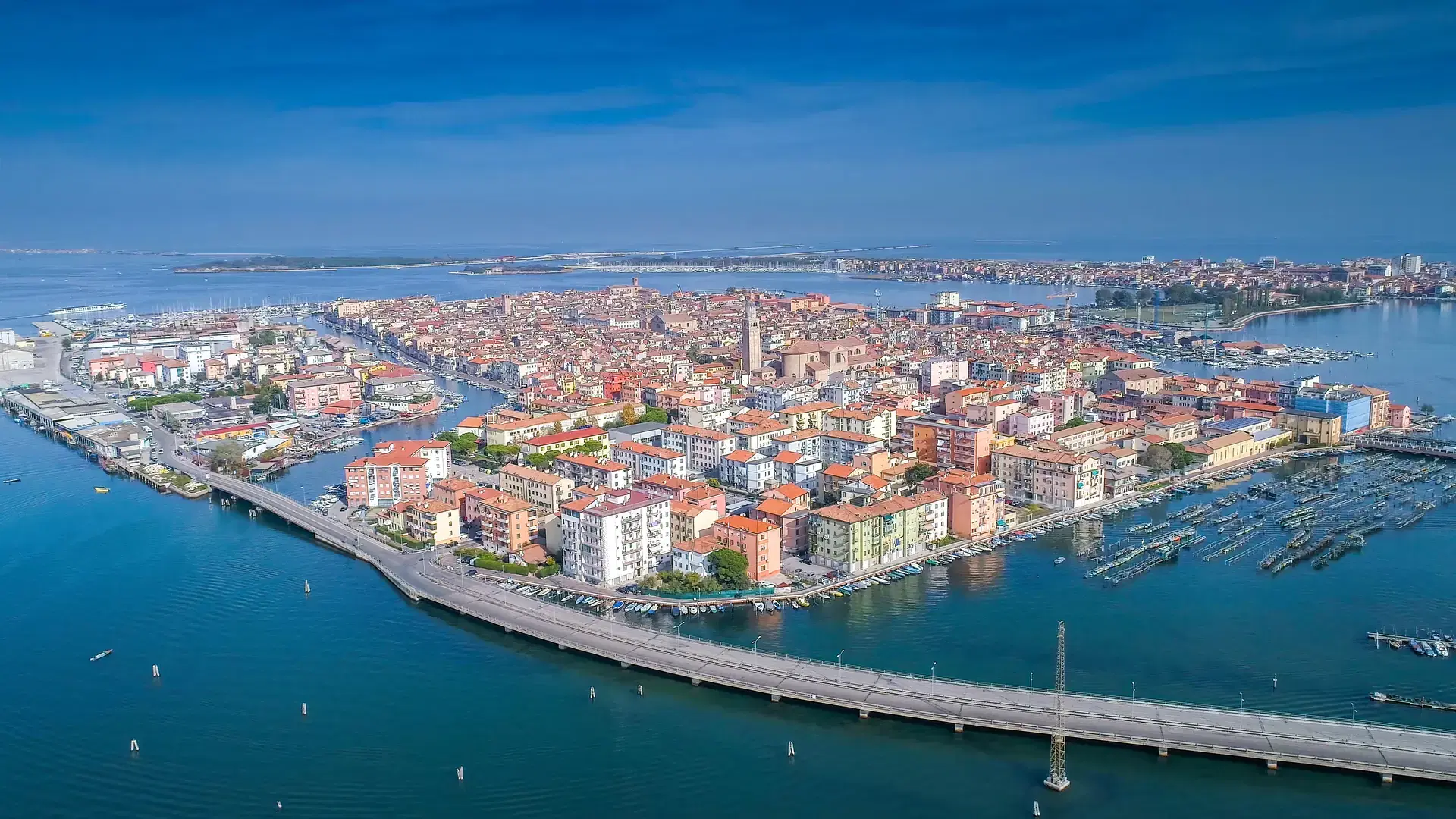 The coastal town of Chiogga in Venice in an aerial shot with the view of the long bridge going into the town the houses and buildings in the middle of the sea in Italy