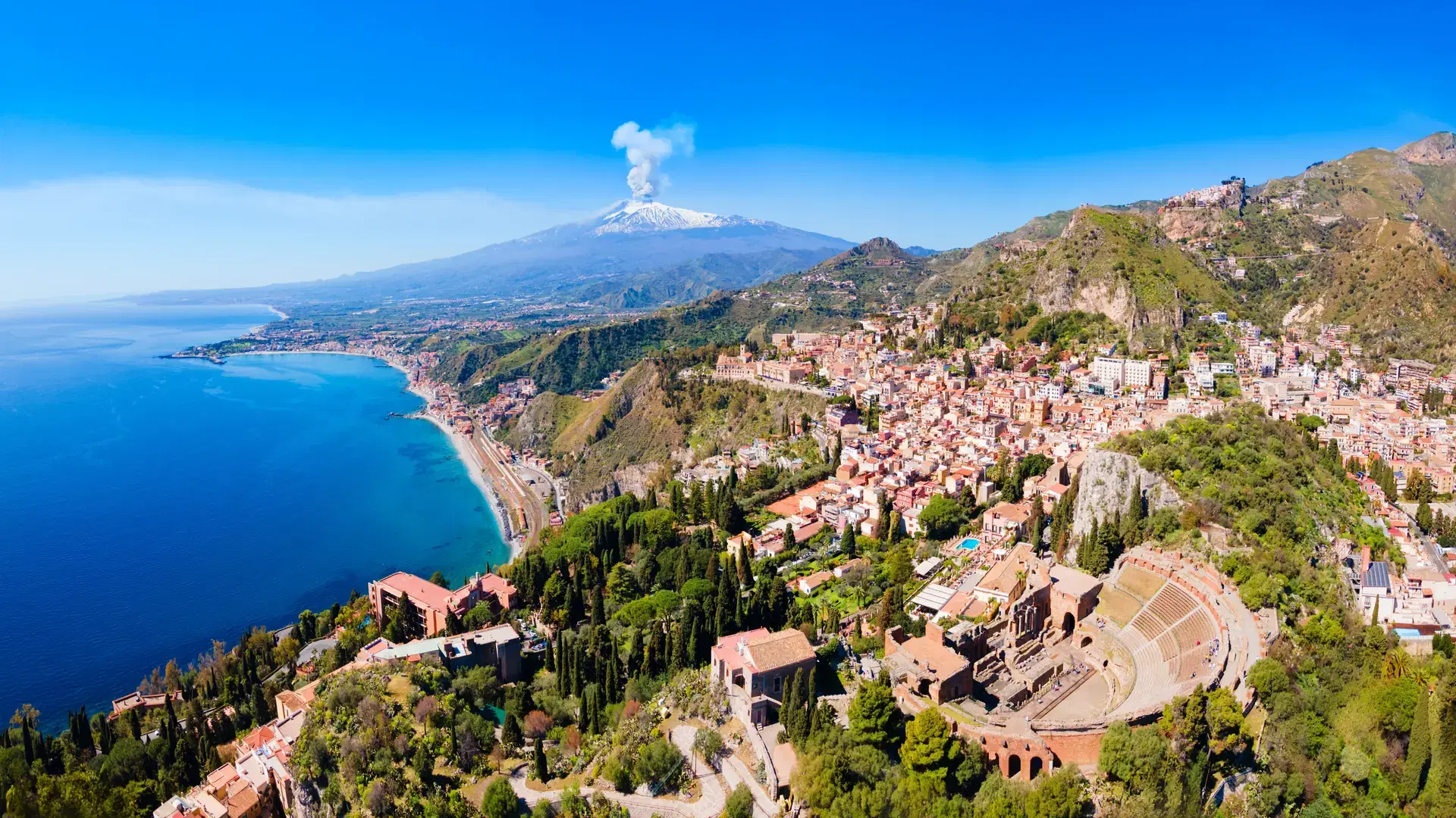 The Ancient Theatre of Taormina or Teatro antico di Taormina and Etna volcano aerial panoramic view, it is an ancient Greek theatre in Taormina city, Sicily island, Italy