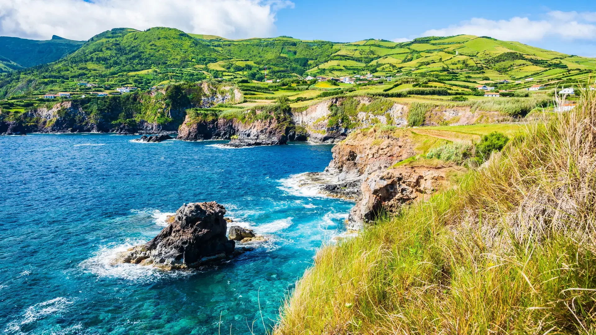 Beautiful bay with rocks on ocean coast with green cliffs at Ponta Delgada, Flores island, Azores, Portugal