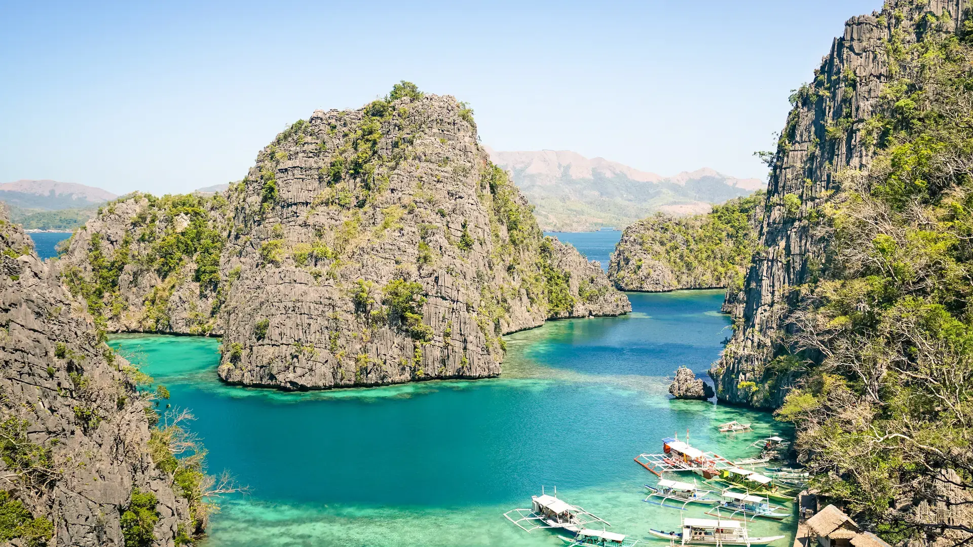 Blue lagoon with longtail boats by Karangan Lake in Coron Palawan - Beautiful tropical destination in Philippines - Travel concept to nature wonders around the world - Warm sunny afternoon color tones