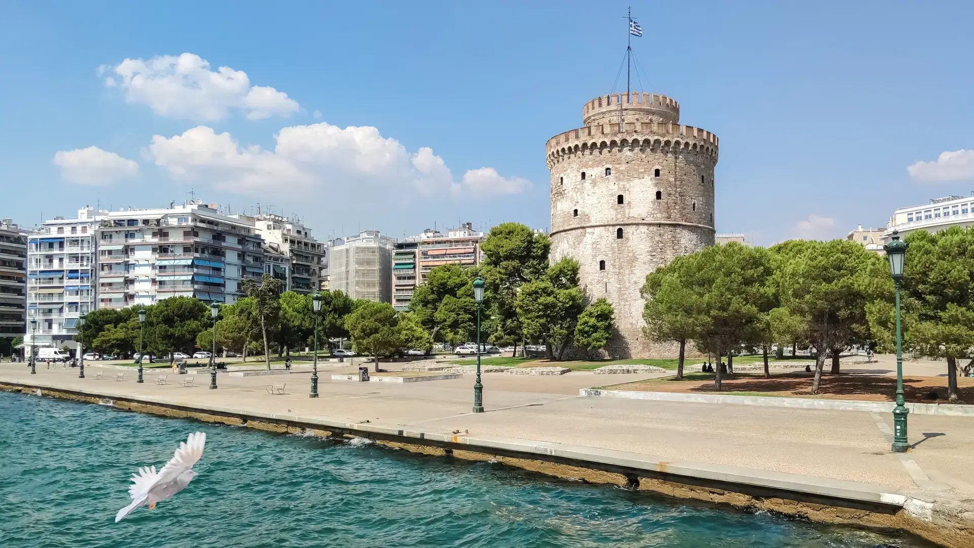 The White Tower of Thessaloniki, a historical monument and famous landmark on the waterfront promenade in Greece, with the Aegean Sea and city skyline on a sunny summer day