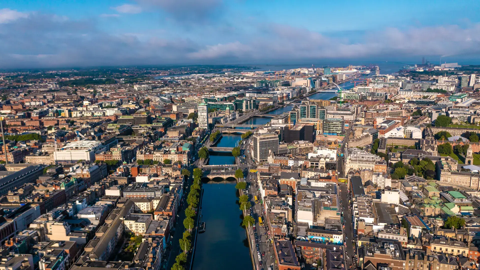 Establisher shot of Dublin skyline with river flowing with bridge connecting two sides of street surrounded by buildings during a cloudy day