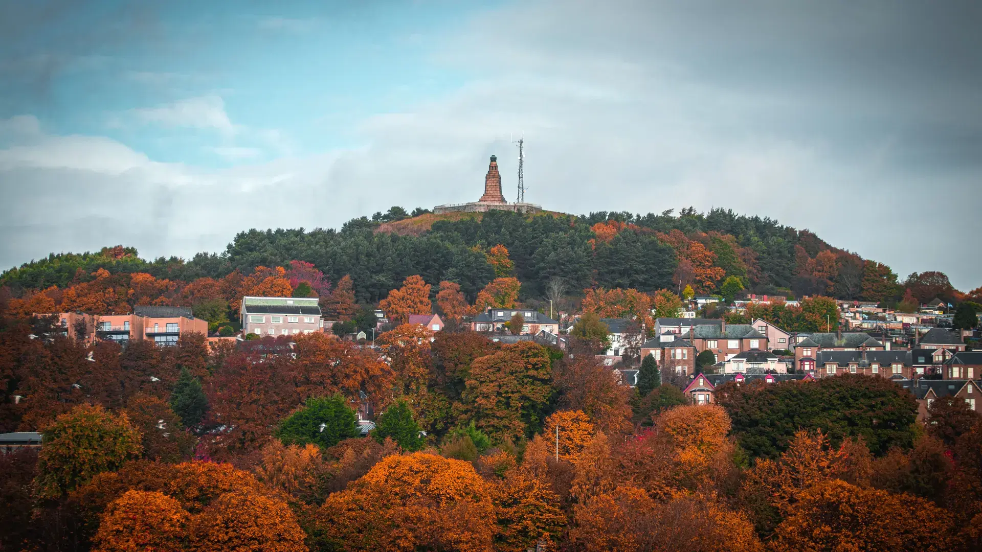 An aerial view of a picturesque cityscape nestled at the base of a lush hillside, Dundee, Scotland