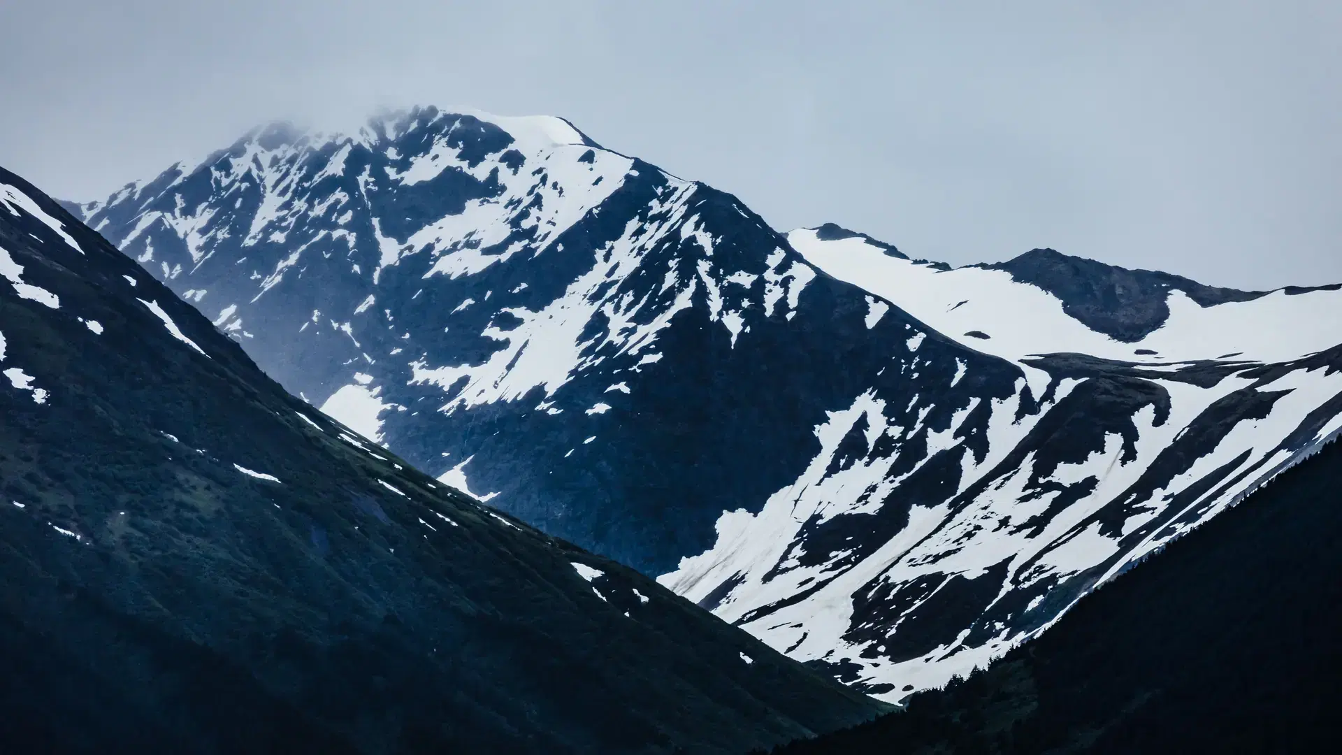 View of Mount Carlisle covered with snow under clouds on Carlisle Island-one of islands of Four Mountains subgroup of Aleutian archipelago