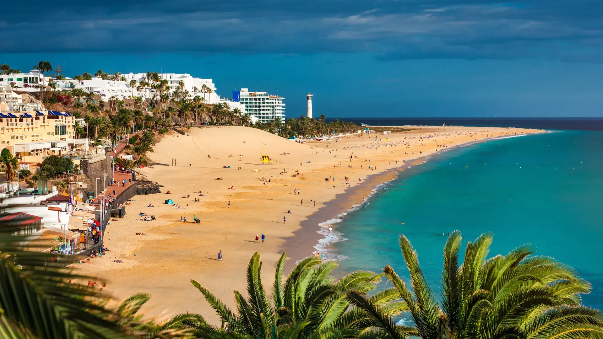 Aerial view of beach in Morro del Jable town (Morro Jable beach) on Fuerteventura island, Canary Islands, Spain. One of the best beach in the Canaries. Motorral lighthouse in distance.
