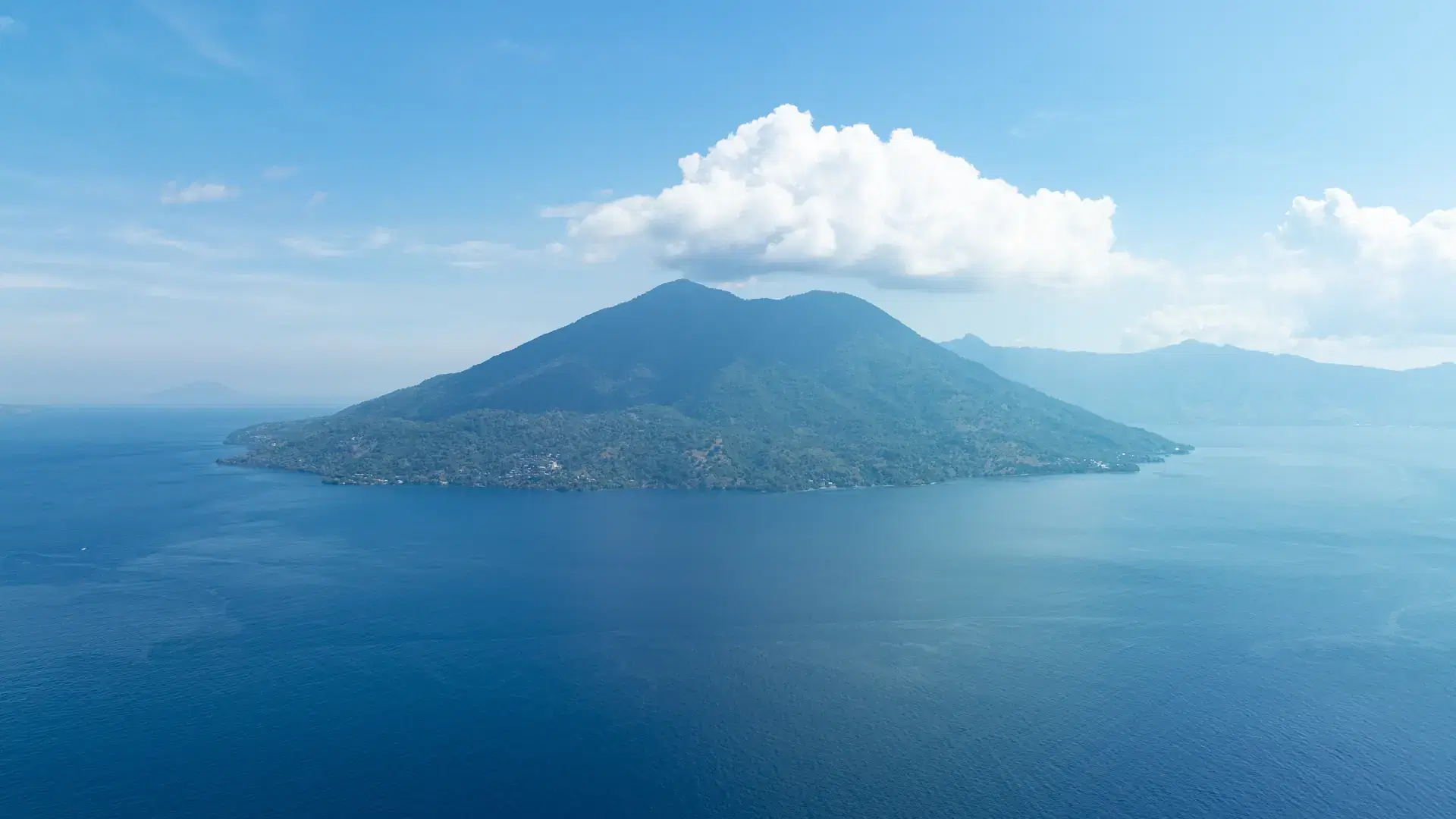 The volcanic island of Pura rises from the Pantar Strait near Alor, Indonesia. This distinctive island is surrounded by coral reefs that receive strong currents that run through the strait.