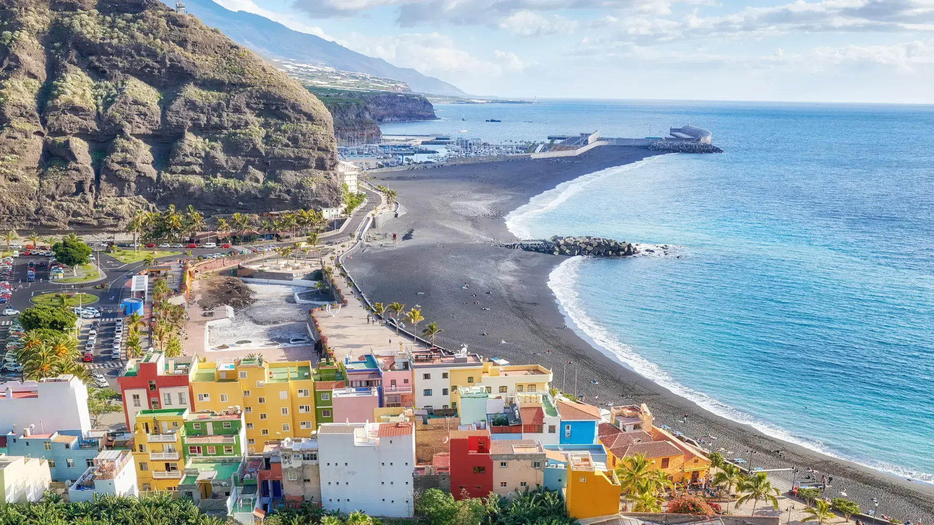 Landscape view of vibrant residential buildings, sea and ocean, a blue sky with clouds and copy space. Scenic mountain and black sand beach of coastal city of Puerto de Tazacorte in La Palma, Spain