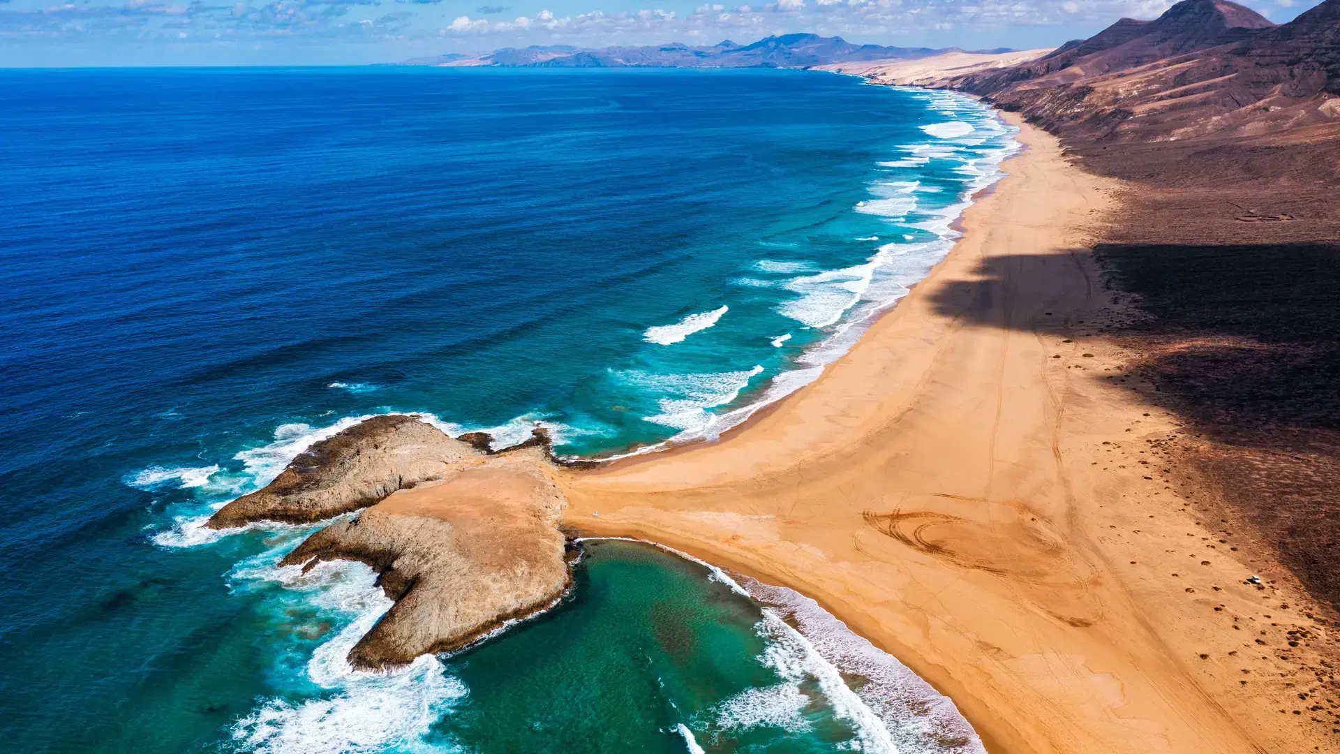 Amazing Cofete beach with endless horizon. Volcanic hills in the background and Atlantic Ocean. Cofete beach, Fuerteventura, Canary Islands, Spain. Playa de Cofete, Fuerteventura, Canary Islands.