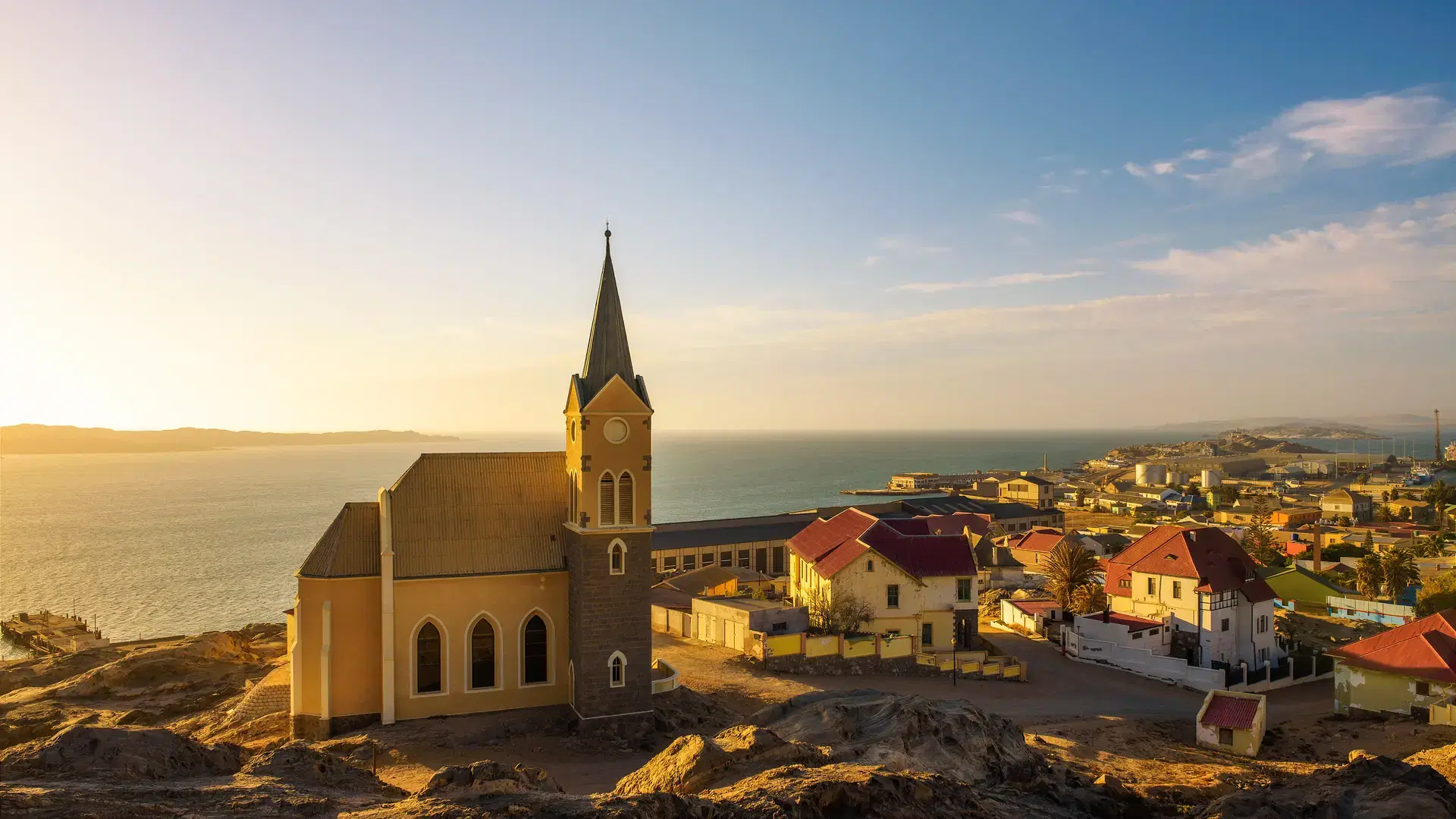 Panoramic view of Luderitz in Namibia at sunset with lutheran church called Felsenkirche and atlantic ocean in the background.