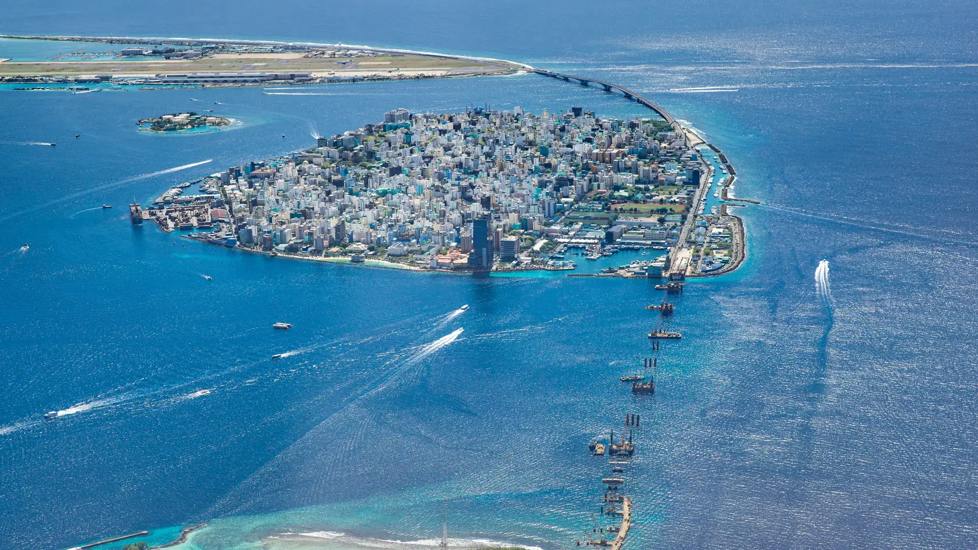 Beautiful aerial view on male the capital city of Maldives. Overcrowded island in Indian ocean blue ocean sea background. Exotic travel destination, airplane window view. Summer travel vacation design
