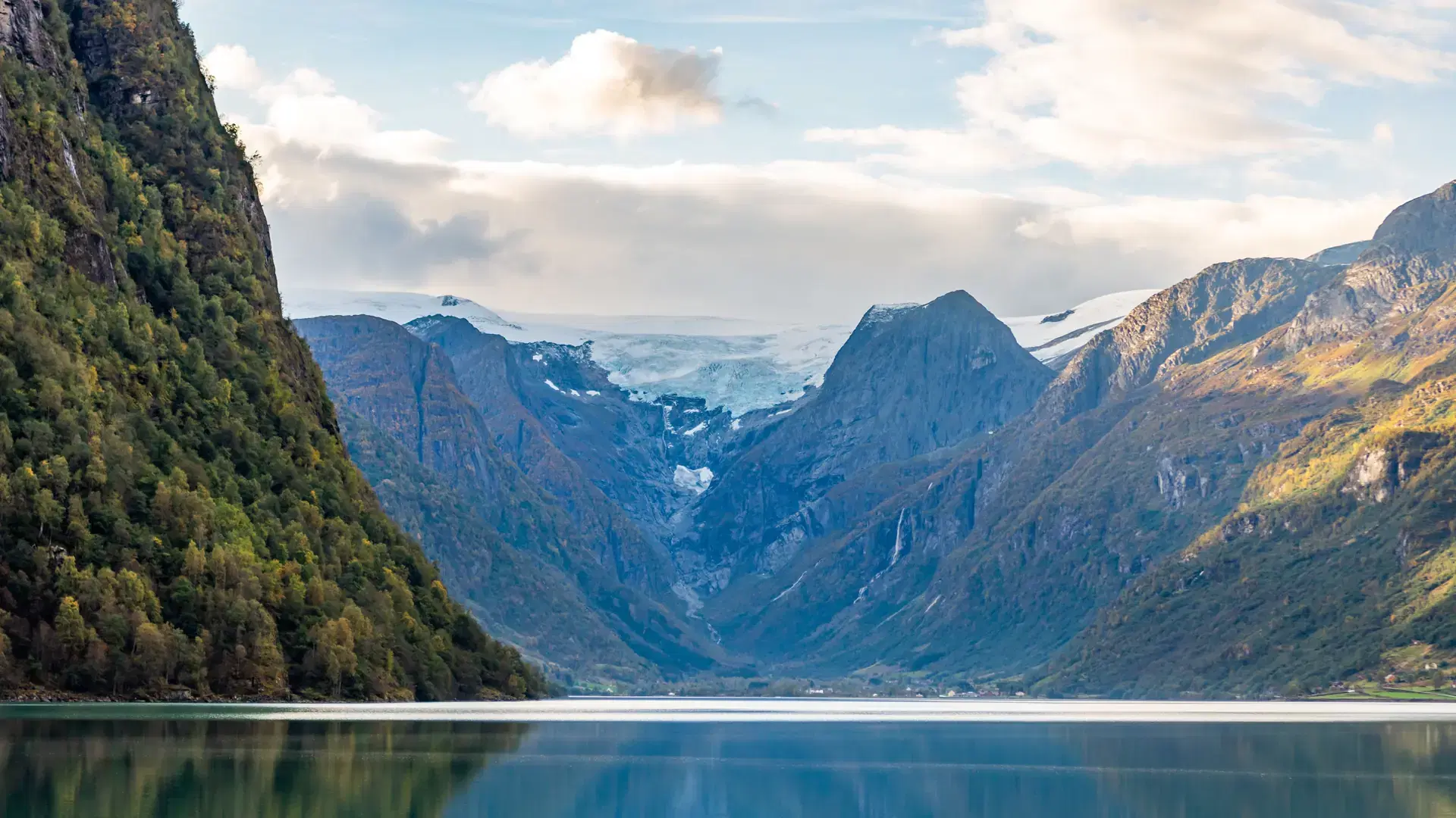 A scenic view of a fjord near Briksdal Glacier under blue cloudy sky in autumn, Norway