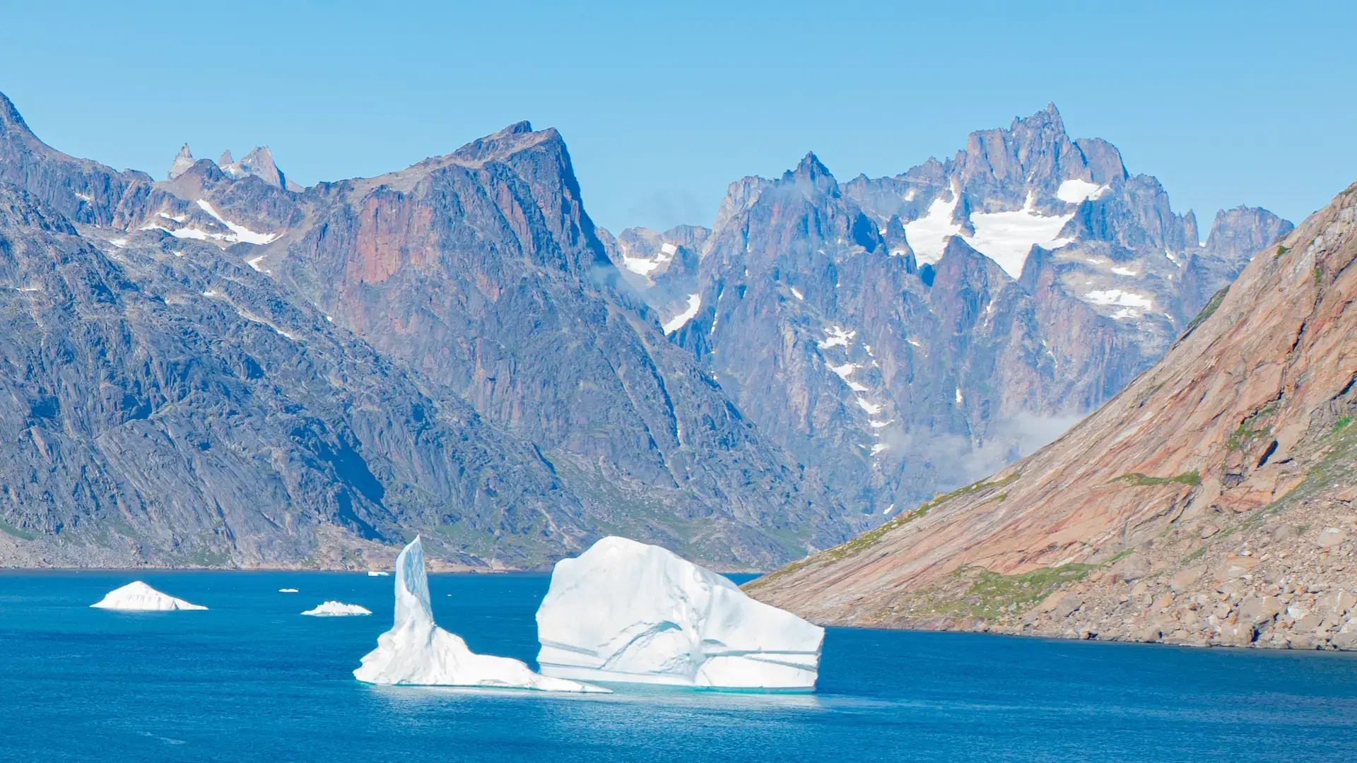 An aerial view of iceberg surrounded by rocky mountains in Prince Christian Sound