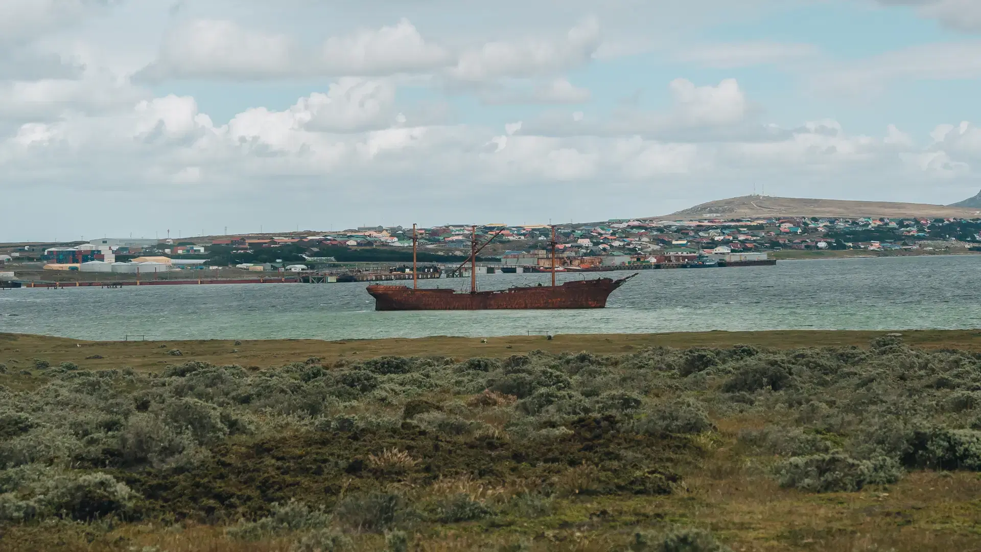 Falkland Islands Lady Elizabeth Rust Covered Shipwreck Bright Day Boat in Harbor Port Stanley Houses in Background