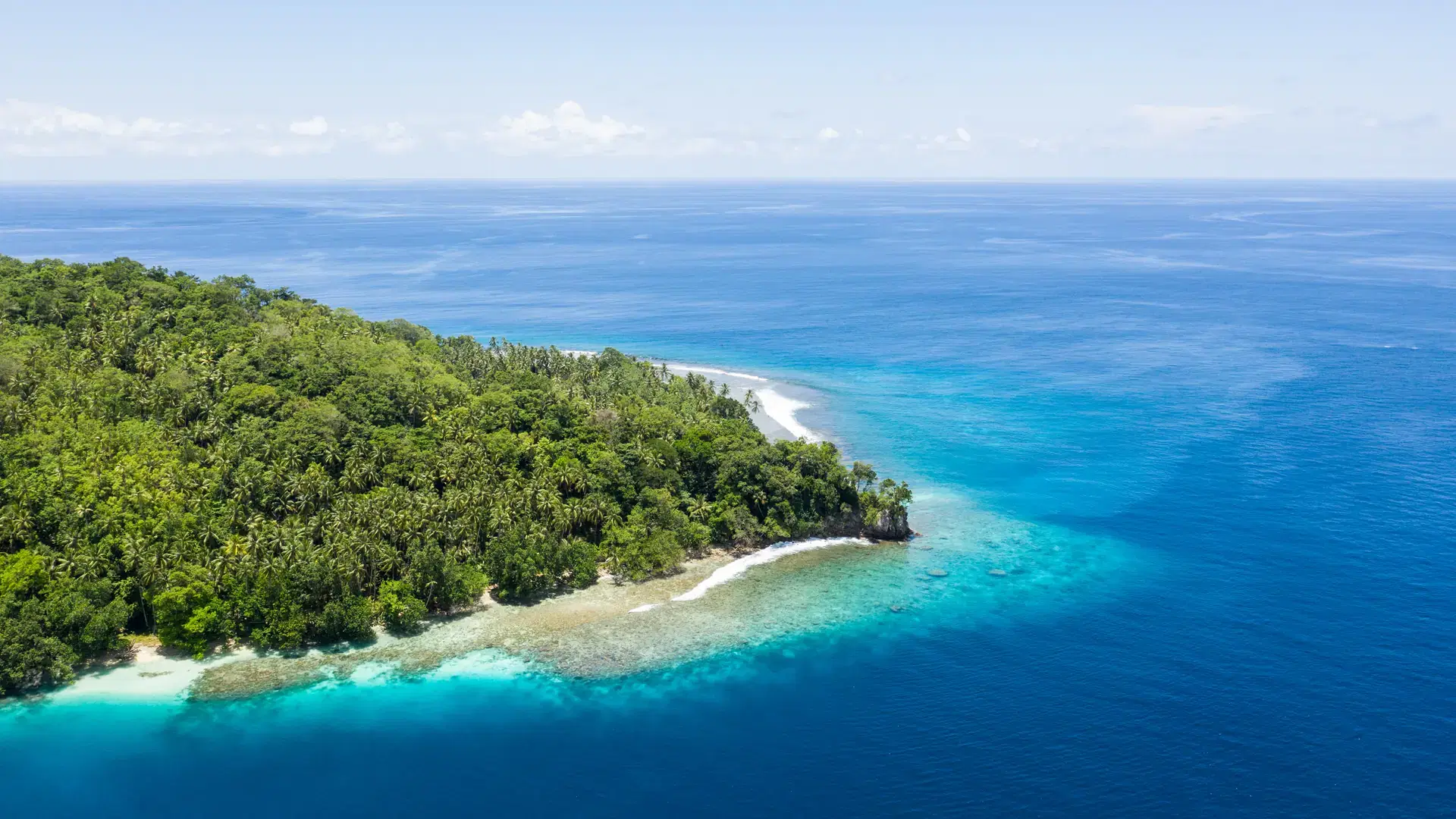 A birds eye view of the remote island of New Ireland in Papua New Guinea shows beautiful fringing reef. This remote area is part of the Coral Triangle due to its high marine biodiversity.