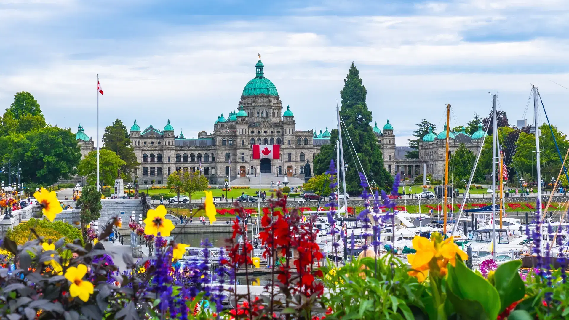 Colorful flowers decorate the inner harbour with the british columbia parliament buildings standing majestically on a sunny summer day in victoria, canada